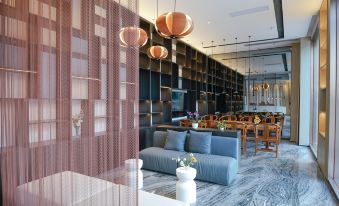 A room with tables and chairs is located inside the lobby or reception area of Hotel Deluxe Prince at Paco  Hotel (Jiangmen Xinhui Times)