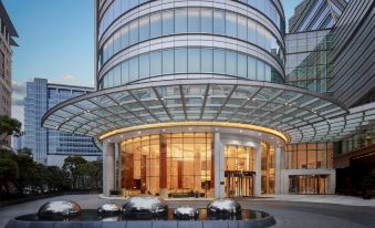 The entrance to a spacious building features glass panels on either side and is accompanied by a courtyard at Shanghai Marriott Marquis City Centre