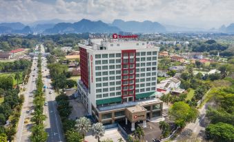 an aerial view of a hotel with a red and white facade , surrounded by mountains at Travelodge Ipoh