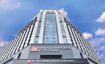 On a sunny day in an urban setting, there are clear front and side views of a large white building at Hilton Garden Inn Guangzhou Tianhe