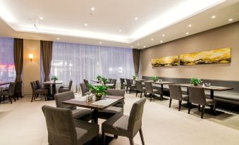 The restaurant is located in the center, alongside an open concept living room, featuring tables and chairs at Home Inn Plus (Shanghai Bund Jinling East Road store)