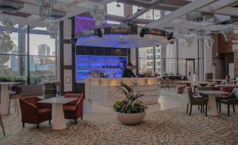 a hotel lobby with a bar , chairs , and tables , as well as a reception desk at Grand Millennium Auckland