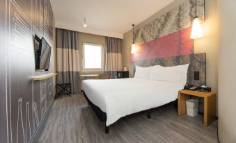 The bedroom features a spacious bed and a desk in the center, complemented by an open concept design at Ibis Hotel (Shanghai New International Expo Center Lianyang Branch)