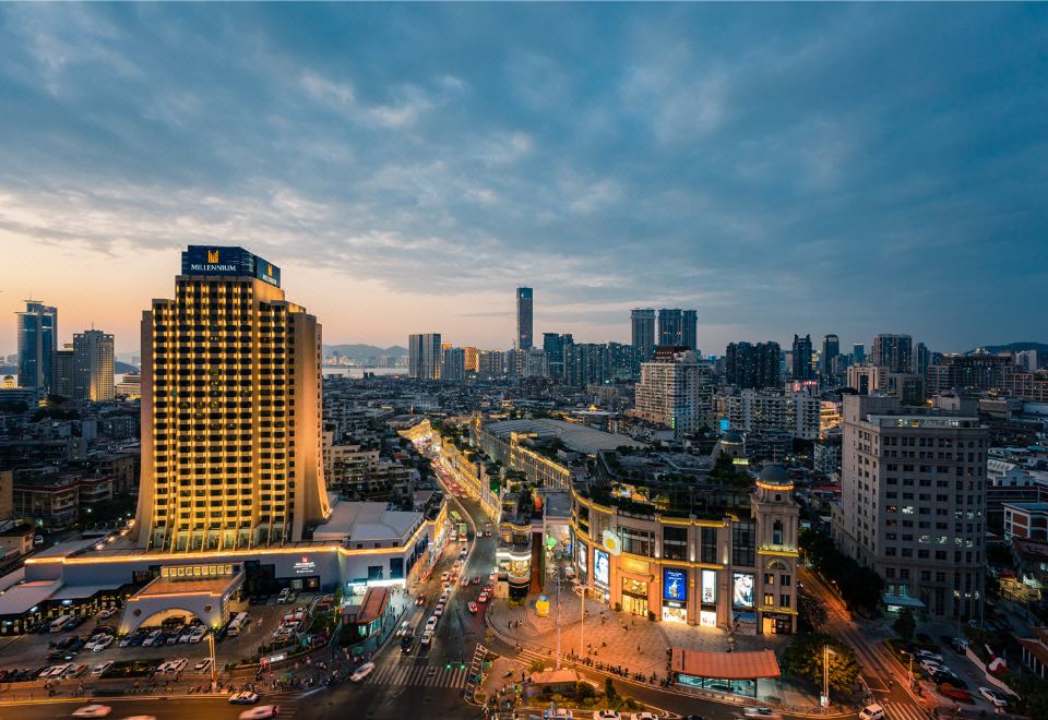 a cityscape at dusk , with tall buildings and a bridge visible in the distance , illuminated by lights at Millennium Harbourview Hotel Xiamen
