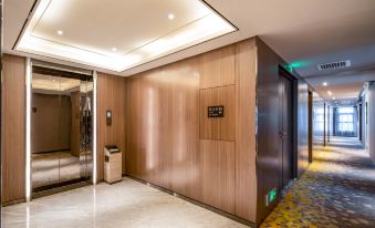 The modern apartment features wood paneled walls and an elevator located at one side of the entrance at Mumian Hotel (Guangzhou Baiyun International Airport)