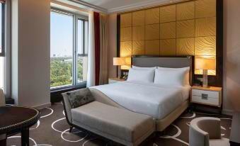 a luxurious hotel room with a large bed , a window offering a view of the city , and various furniture pieces at Waldorf Astoria Berlin