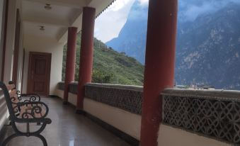 The alpine Chinese-style building features a balcony with chairs and a table that overlooks the mountains at Tina's Youth Hostel