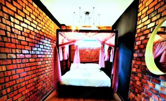 a cozy bedroom with a canopy bed in the center , surrounded by brick walls and wooden flooring at Petak Padin Cottage by The Pool
