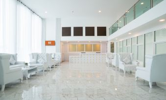 The upscale hotel features a spacious, white lobby or reception area with numerous chairs at B2 Phuket Premier Hotel