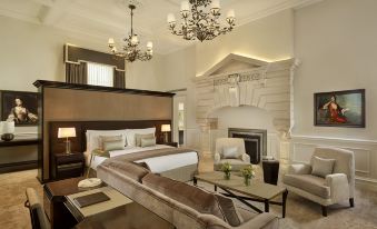 a luxurious bedroom with a large bed , a fireplace , and a comfortable couch in the living room at The Langley, a Luxury Collection Hotel, Buckinghamshire