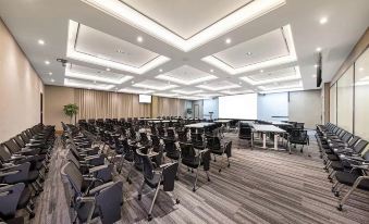 a spacious conference room with rows of tables in the front, adjacent to the meeting area at ICON LAB Hotel Shenzhen Futian