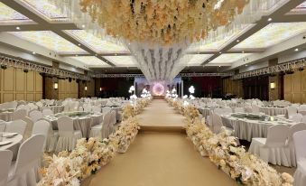 a large banquet hall with a long aisle and tables covered in white tablecloths and flowers at Gushi Oriental Earl Hotel (Yucheng Avenue Genqin Culture Park)