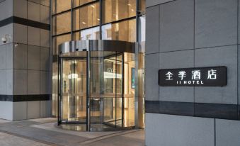 The building has a glass fronted door with a sign and an elevator at the entrance at All Seasons Hotel (Guangzhou Tianhe Sports Center Branch)