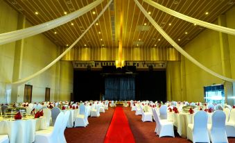 a large , empty banquet hall with rows of white tables and red tablecloths , set for a formal event at Duyong Marina & Resort