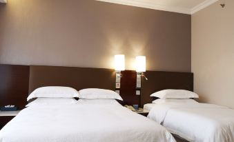 The bedroom features two white beds with a brown bedspread on the double-sized headboard at Ocean Hotel