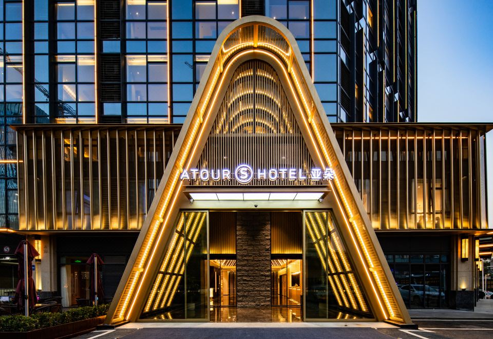 The entrance to a hotel is illuminated at night, featuring a front door and glass facade at Atour S Hotel