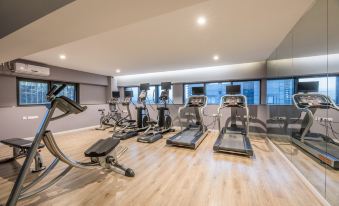 a gym with various exercise equipment , including treadmills and stationary bikes , in a spacious room with large windows at Suisse Apartment Hotel Suzhou Jinji Lake Expo Center