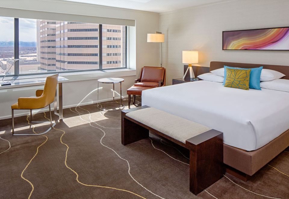 a hotel room with a large bed , a couch , and a tv . also a dining table in the room at Grand Hyatt Denver