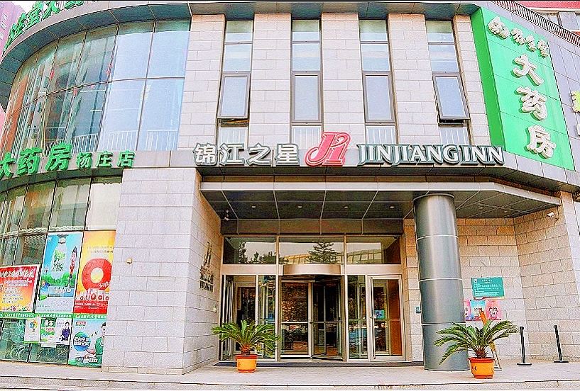 The front entrance of a hotel is adorned with an oriental sign, while other buildings surround it at Jinjiang Inn(Beijing Tongzhou Beiyuan Subway Station)