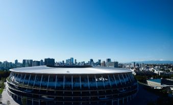 a large stadium with a blue sky in the background and city buildings surrounding it at Mitsui Garden Hotel Jingugaien Tokyo Premier