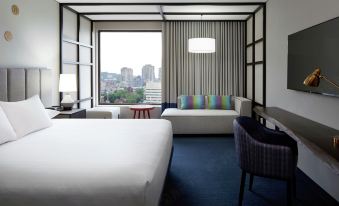 a hotel room with two beds , a couch , and a window overlooking a cityscape outside at Doubletree by Hilton Montreal