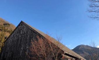 a wooden barn with a blue sky and green trees in front of it , possibly a mountain at Yufuin Bath Satoyamasafu
