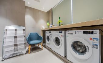 A room with chairs and a washing machine is located in the adjacent laundry area, accessible through an open doorway at Homeinn Selected Hotel (Shanghai The Bund City God Temple)