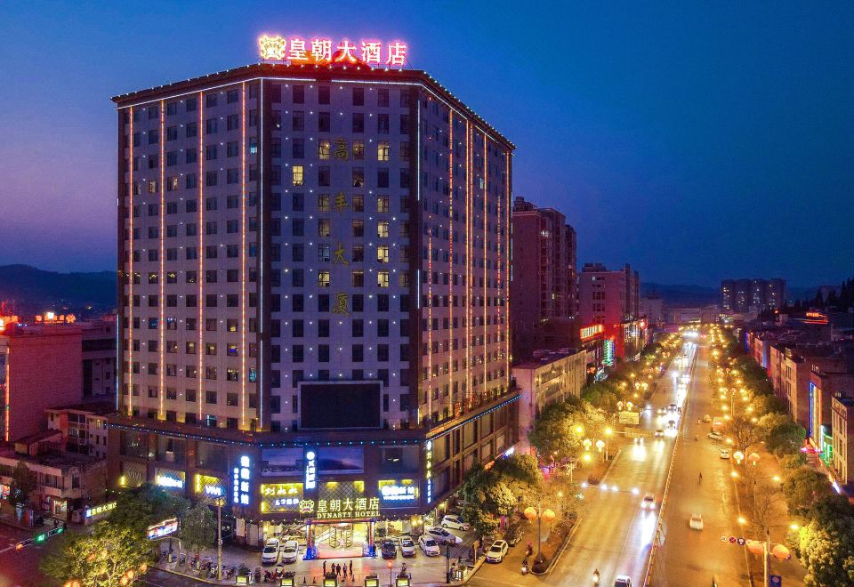 a large hotel building in the middle of a busy city street , surrounded by cars and people at Dynasty Hotel