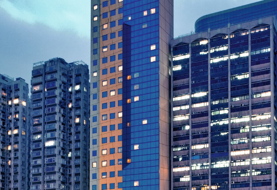 A photo of a large building surrounded by tall buildings at night at Ibis Hong Kong North Point
