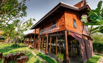 "a wooden building with a sign that reads "" sriwijaya hotel "" is surrounded by green grass and trees" at Maikaew Damnoen Resort