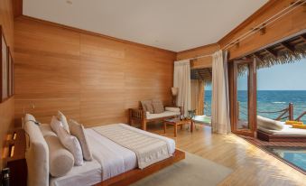 a modern bedroom with wooden walls and a large window offering a view of the ocean at Adaaran Select Meedhupparu - with 24Hrs Premium All Inclusive