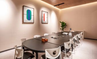 The conference room features white walls, wooden paneling, and an oval table that can accommodate four people at UrCove by HYATT Shanghai Jing'an