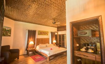 a cozy bedroom with a wooden floor , white beddings , and various decorations , including a bed , nightstands , and lamps at Tasik Ria Resort