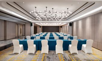 A spacious event room is arranged with blue chairs and white tablecloths at Kasion K Hotel Yiwu