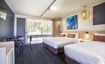 a modern hotel room with two beds , a desk , and large windows , decorated with blue walls and curtains at Nightcap at Gateway Hotel