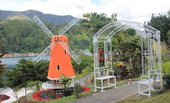 a beautiful garden with a red windmill in the center , surrounded by various plants and flowers at Khas Parapat