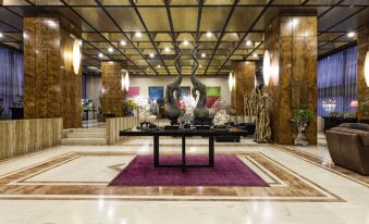 a grand hotel lobby with marble floors , a black marble fountain , and a purple carpet at President Hotel