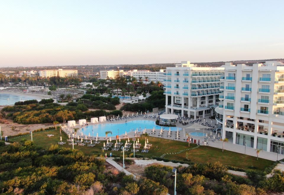 a large swimming pool is surrounded by a hotel and other buildings in the background at NissiBlu Beach Resort