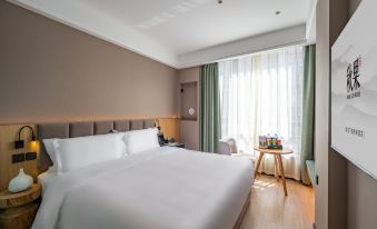 The modern-style bedroom features a double bed and a large window that overlooks the rest area at Qiuguo Hotel (Beijing Sanlitun Gongti Branch)