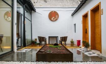 a courtyard with a stone floor , potted plants , and a round sign on the wall at yhz