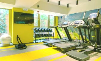 The well-lit gym in the center features treadmills and large windows at OASIS AVENUE – A GDH HOTEL