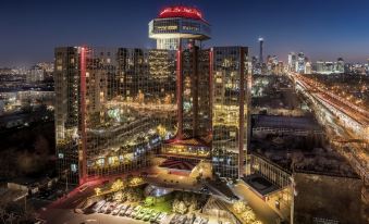 At night, there is a panoramic view of the city with tall buildings and an outdoor seating area at The Great Wall Hotel Beijing