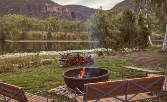 a fire pit surrounded by benches and chairs , with a view of a lake in the background at Mt Mulligan Lodge