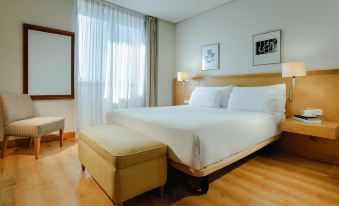 a large bed with white sheets and a wooden headboard is in a room with a bench at Hesperia Vigo