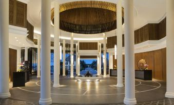 a modern , well - lit lobby with white columns and a large circular light fixture hanging from the ceiling at Avani Sepang Goldcoast Resort