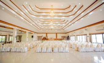 a large , empty banquet hall with white chairs and tables set up for an event at Chiangkhan River Mountain Resort