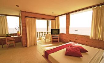 a hotel room with a king - sized bed , a television , and a view of the ocean at Antulang Beach Resort