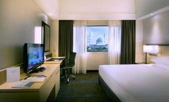 a hotel room with a large bed , a desk , a chair , and a window overlooking the city at Concorde Hotel Shah Alam