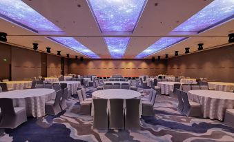 a large , well - lit room with multiple tables and chairs set up for an event or meeting at Guangzhou Hotel