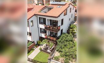 aerial view of a white building with red tile roofs and balconies , surrounded by green grass and trees at Villa Varosh